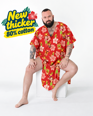 Bearded man seated in the Cheeky Tiki caftan, a red hibiscus and tiki print in thick cotton