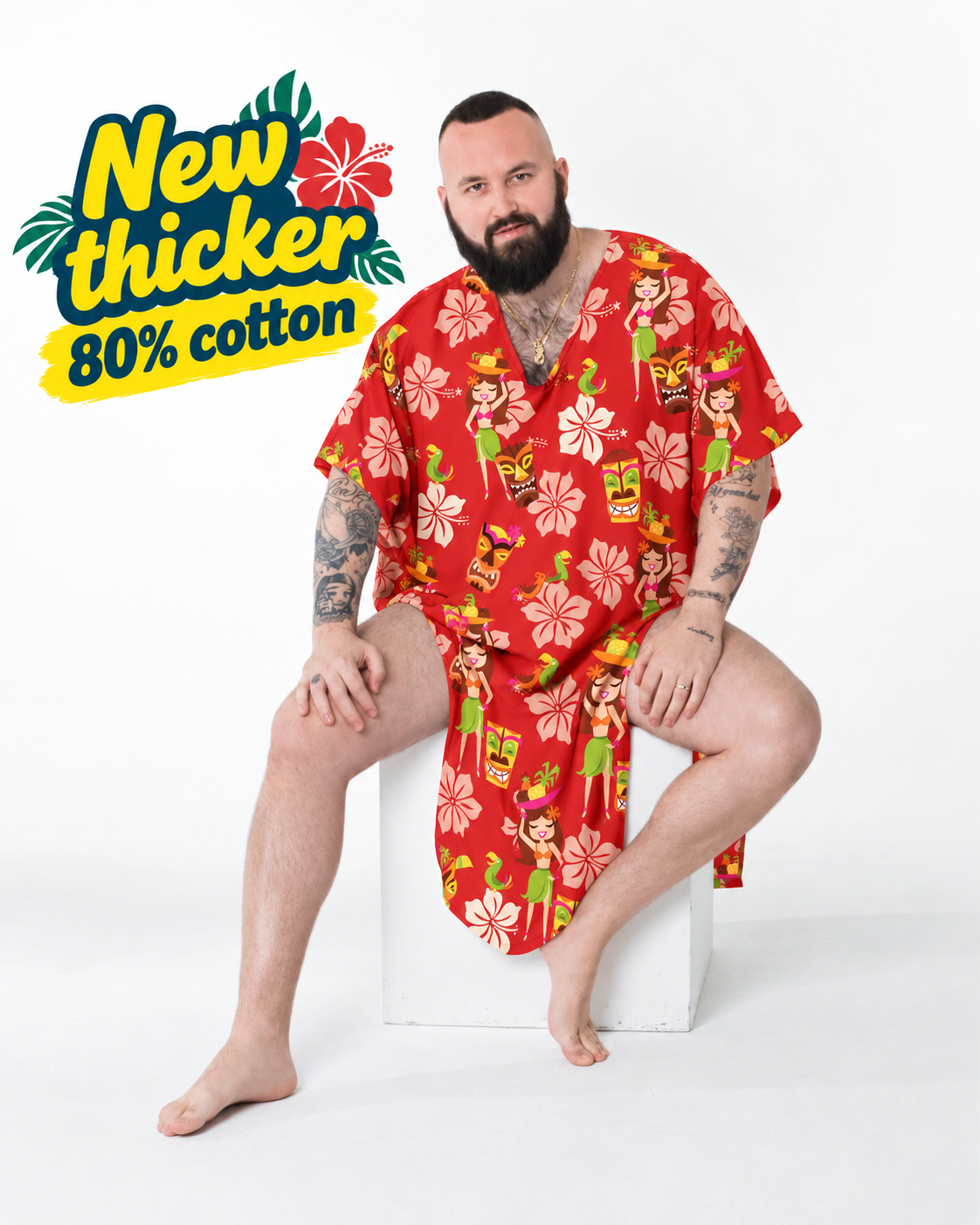 Bearded man seated in the Cheeky Tiki caftan, a red hibiscus and tiki print in thick cotton